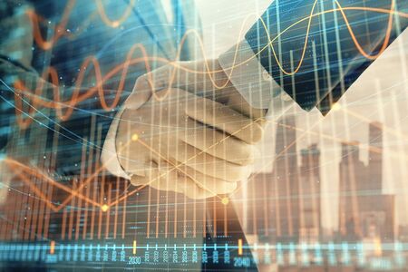 Double exposure of financial graph on cityscape background with two businessman handshake. Concept of stock market dealの写真素材