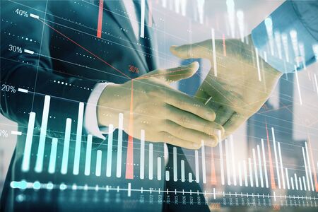 Double exposure of financial graph on cityscape background with two businessman handshake. Concept of stock market dealの写真素材