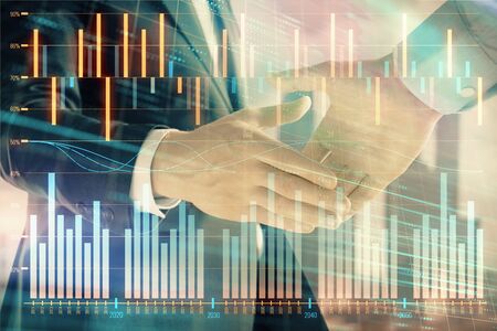 Double exposure of financial graph on cityscape background with two businessman handshake. Concept of stock market dealの写真素材