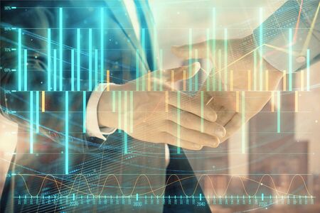 Double exposure of financial graph on cityscape background with two businessman handshake. Concept of stock market dealの写真素材