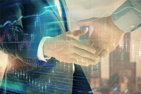 Double exposure of financial graph on cityscape background with two businessman handshake. Concept of stock market dealの写真素材