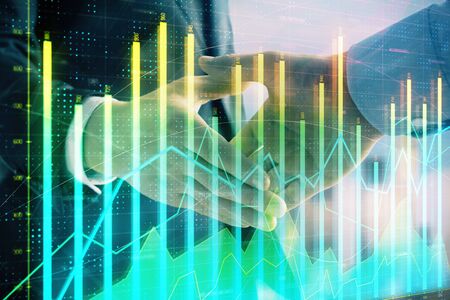 Double exposure of financial graph on cityscape background with two businessman handshake. Concept of stock market dealの写真素材