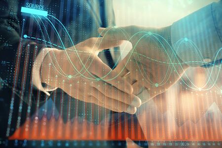 Double exposure of financial graph on cityscape background with two businessman handshake. Concept of stock market dealの写真素材