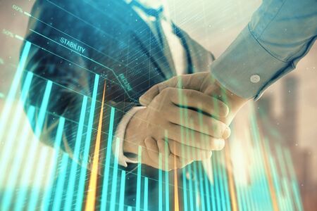 Double exposure of financial graph on cityscape background with two businessman handshake. Concept of stock market dealの写真素材