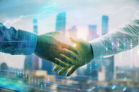 Double exposure of financial graph on cityscape background with two businessman handshake. Concept of stock market dealの写真素材