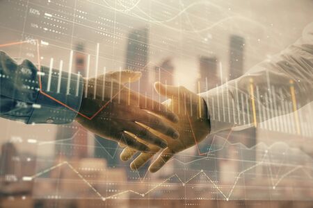 Double exposure of financial graph on cityscape background with two businessman handshake. Concept of stock market dealの写真素材