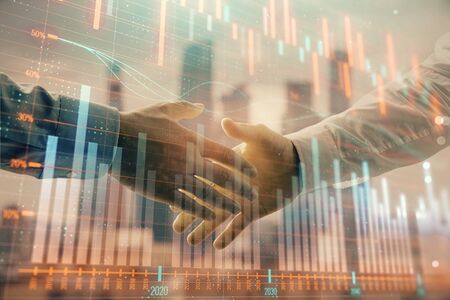 Double exposure of financial graph on cityscape background with two businessman handshake. Concept of stock market dealの写真素材