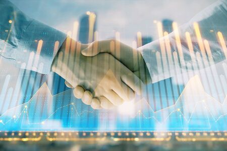 Double exposure of financial graph on cityscape background with two businessman handshake. Concept of stock market dealの写真素材