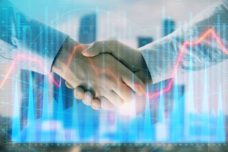 Double exposure of financial graph on cityscape background with two businessman handshake. Concept of stock market dealの写真素材