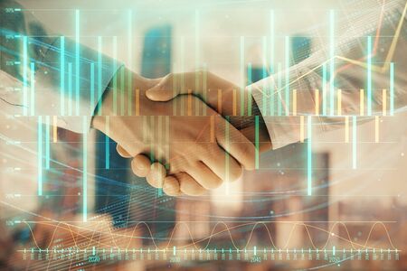 Double exposure of financial graph on cityscape background with two businessman handshake. Concept of stock market dealの写真素材