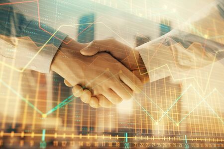 Double exposure of financial graph on cityscape background with two businessman handshake. Concept of stock market dealの写真素材