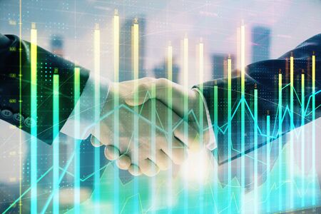 Double exposure of financial graph on cityscape background with two businessman handshake. Concept of stock market dealの写真素材