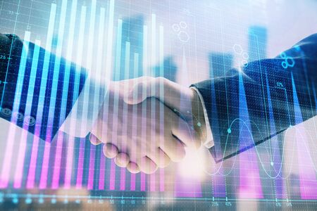 Double exposure of financial graph on cityscape background with two businessman handshake. Concept of stock market dealの写真素材