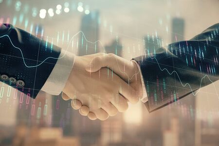 Double exposure of financial graph on cityscape background with two businessman handshake. Concept of stock market dealの写真素材