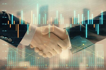 Double exposure of financial graph on cityscape background with two businessman handshake. Concept of stock market dealの写真素材