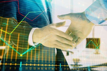 Multi exposure of financial graph on office background with two businessmen handshake. Concept of success in businessの写真素材