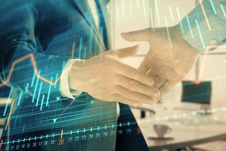 Multi exposure of financial graph on office background with two businessmen handshake. Concept of success in businessの写真素材