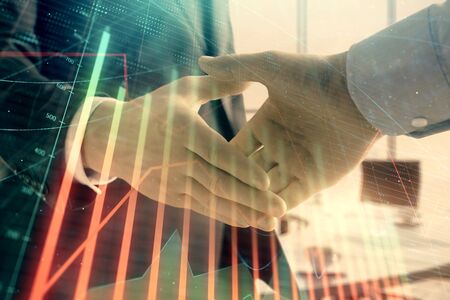 Multi exposure of financial graph on office background with two businessmen handshake. Concept of success in businessの写真素材