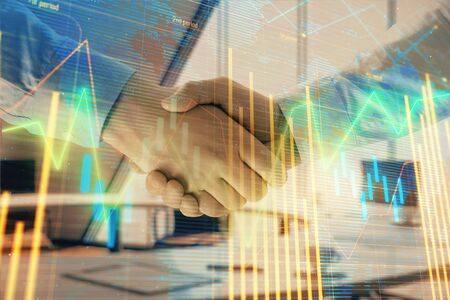 Multi exposure of financial chart and map on office background with two businessmen handshake. Concept of success in businessの写真素材