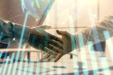 Multi exposure of financial chart and map on office background with two businessmen handshake. Concept of success in businessの写真素材