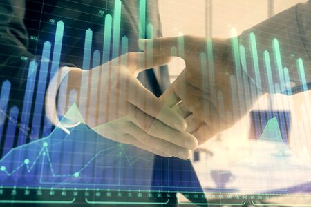 Multi exposure of financial graph on office background with two businessmen handshake. Concept of success in businessの写真素材