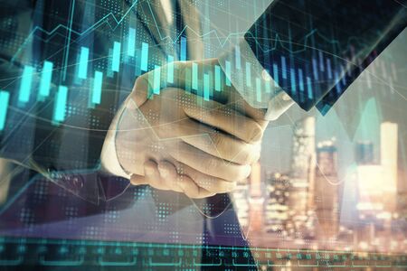 Double exposure of financial chart on cityscape background with two businessmen handshake. Concept of financial analysis and investment opportunitiesの写真素材