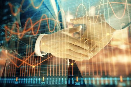 Double exposure of financial chart on cityscape background with two businessmen handshake. Concept of financial analysis and investment opportunitiesの写真素材