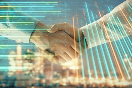Double exposure of financial chart on cityscape background with two businessmen handshake. Concept of financial analysis and investment opportunitiesの写真素材