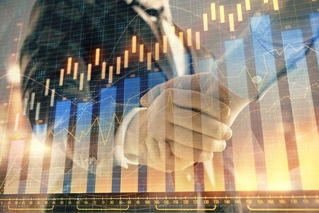 Double exposure of financial chart on cityscape background with two businessmen handshake. Concept of financial analysis and investment opportunitiesの写真素材