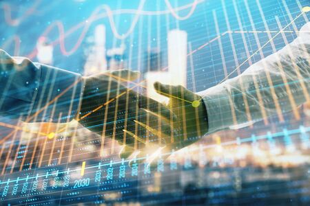 Double exposure of financial chart on cityscape background with two businessmen handshake. Concept of financial analysis and investment opportunitiesの写真素材