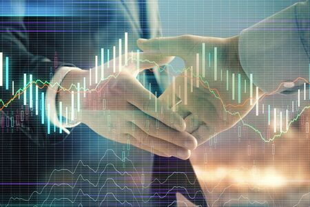 Double exposure of financial chart on cityscape background with two businessmen handshake. Concept of financial analysis and investment opportunitiesの写真素材