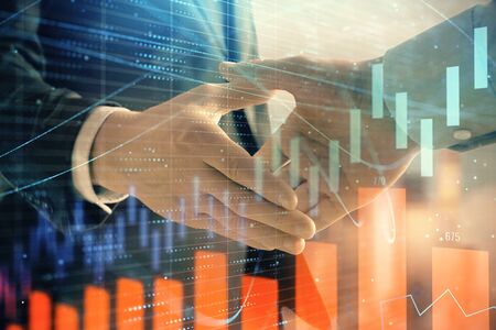 Double exposure of financial graph on cityscape background with two businessman handshake. Concept of stock market dealの写真素材