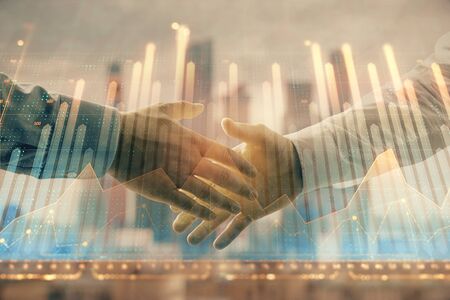 Double exposure of financial graph on cityscape background with two businessman handshake. Concept of stock market dealの写真素材