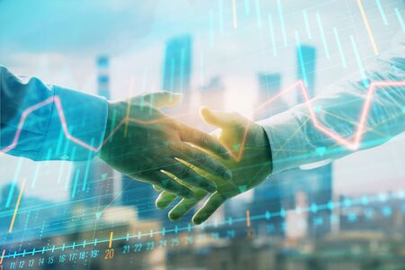 Double exposure of financial graph on cityscape background with two businessman handshake. Concept of stock market dealの写真素材