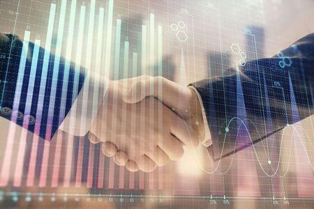Double exposure of financial graph on cityscape background with two businessman handshake. Concept of stock market dealの写真素材