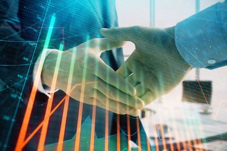 Multi exposure of financial graph on office background with two businessmen handshake. Concept of success in businessの写真素材