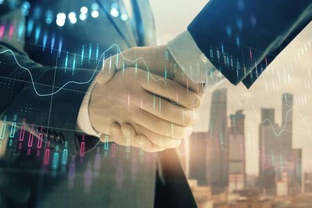 Double exposure of financial graph on cityscape background with two businessman handshake. Concept of stock market dealの写真素材