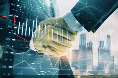 Double exposure of financial graph on cityscape background with two businessman handshake. Concept of stock market dealの写真素材