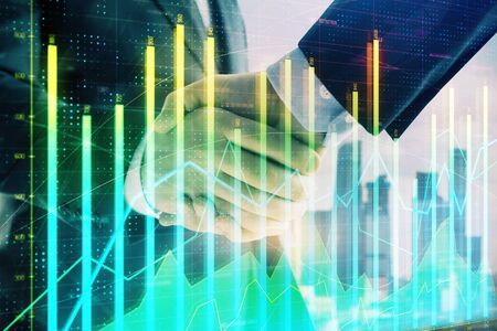 Double exposure of financial graph on cityscape background with two businessman handshake. Concept of stock market dealの写真素材