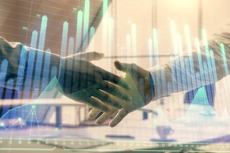 Multi exposure of financial graph on office background with two businessmen handshake. Concept of success in businessの写真素材