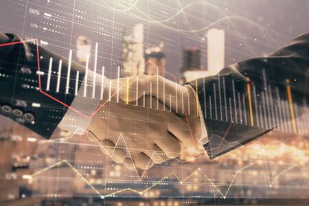 Double exposure of financial graph on cityscape background with two businessman handshake. Concept of stock market dealの写真素材