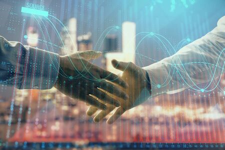 Double exposure of financial chart on cityscape background with two businessmen handshake. Concept of financial analysis and investment opportunitiesの写真素材