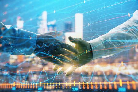 Double exposure of financial chart on cityscape background with two businessmen handshake. Concept of financial analysis and investment opportunitiesの写真素材