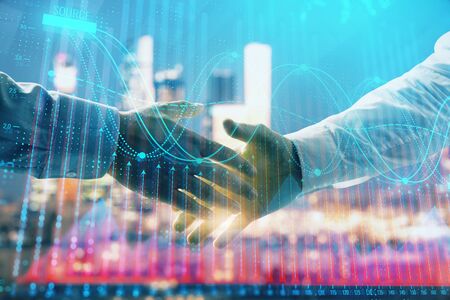Double exposure of financial chart on cityscape background with two businessmen handshake. Concept of financial analysis and investment opportunitiesの写真素材