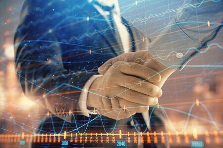 Double exposure of financial chart on cityscape background with two businessmen handshake. Concept of financial analysis and investment opportunitiesの写真素材