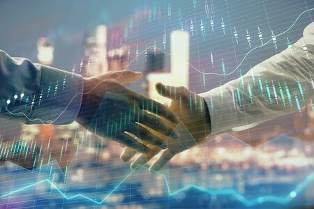 Double exposure of financial chart on cityscape background with two businessmen handshake. Concept of financial analysis and investment opportunitiesの写真素材