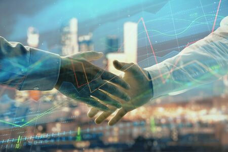Double exposure of financial chart on cityscape background with two businessmen handshake. Concept of financial analysis and investment opportunitiesの写真素材