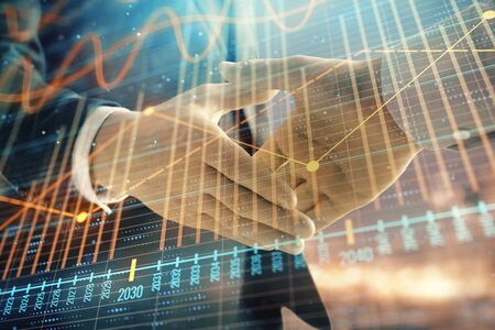 Double exposure of financial chart on cityscape background with two businessmen handshake. Concept of financial analysis and investment opportunitiesの写真素材