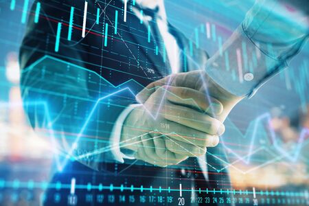 Double exposure of financial chart on cityscape background with two businessmen handshake. Concept of financial analysis and investment opportunitiesの写真素材