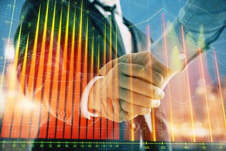 Double exposure of financial chart on cityscape background with two businessmen handshake. Concept of financial analysis and investment opportunitiesの写真素材